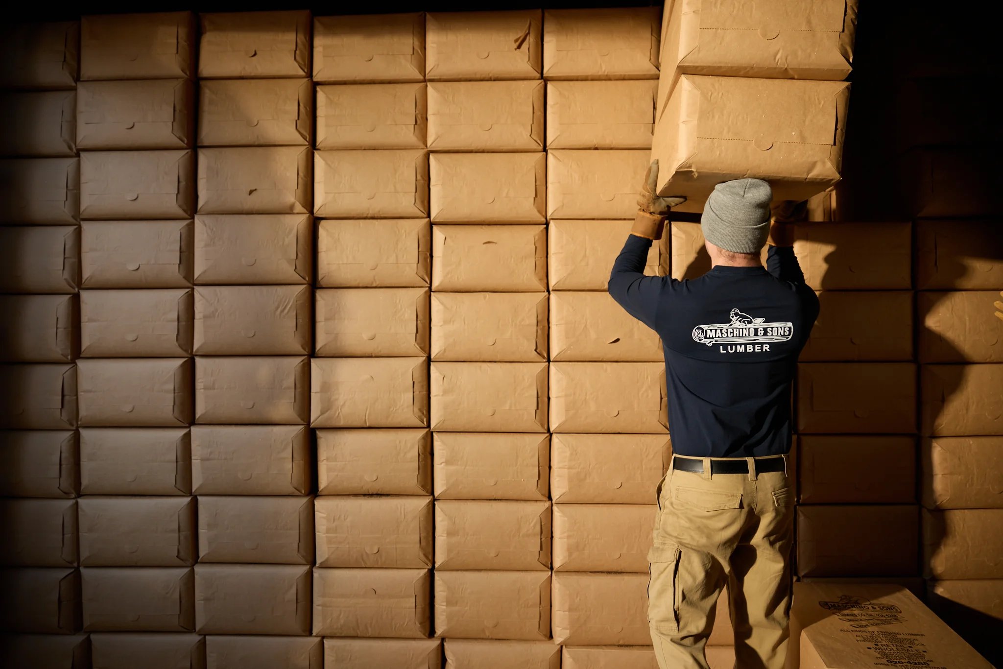 A Maschino & Sons Lumber employee stacking bagged wood shavings